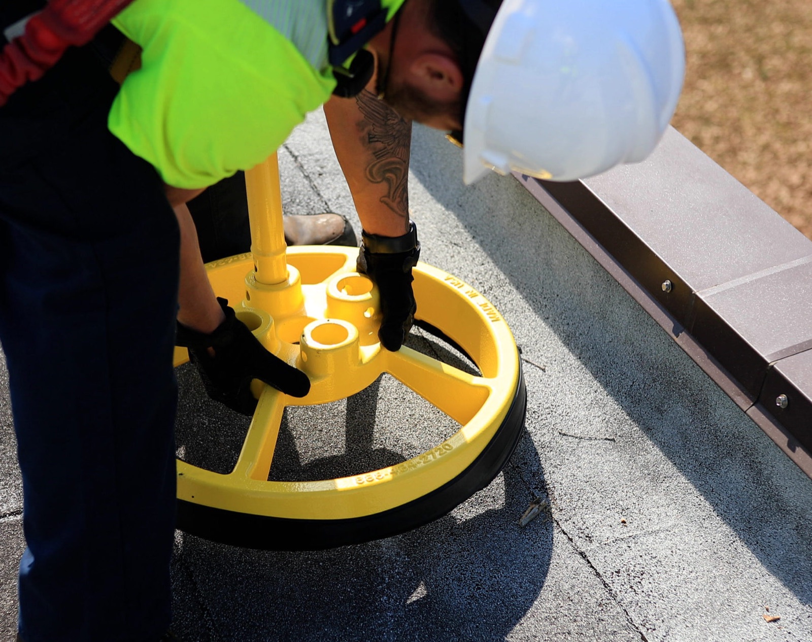 Installer setting the round non-penetrating counterweight base of a guardrail directly on the roof membrane